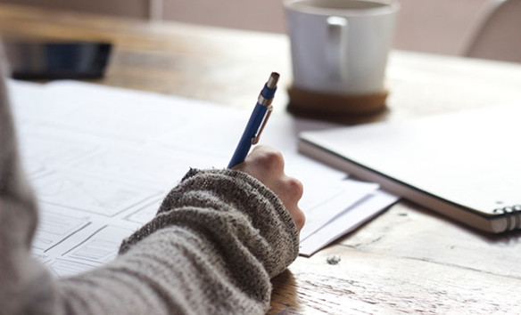 writing at a desk with a cup of coffee